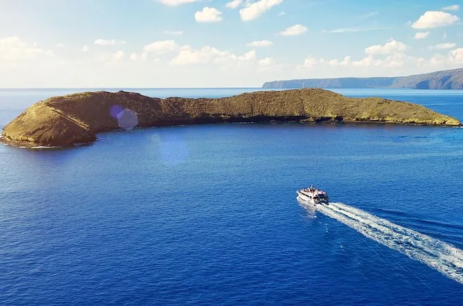 Molokini crater seen from a boat, with a white wake in the foreground