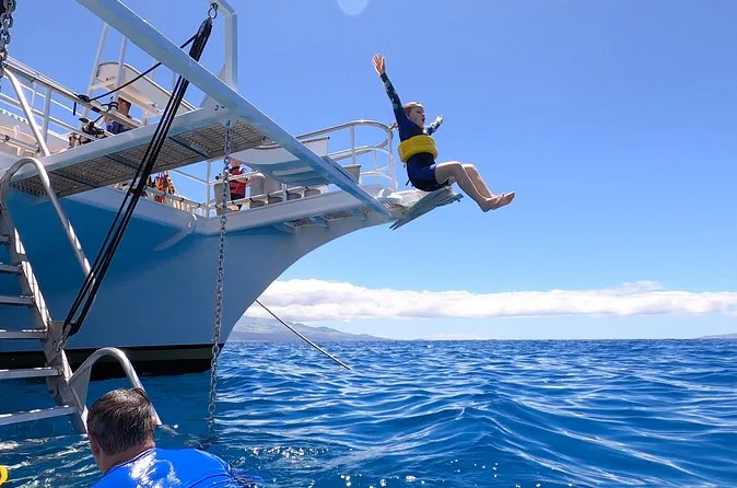 A guest jumping from the bow of the Pride of Maui into blue water
